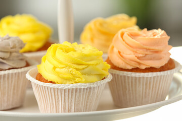 Tasty cupcakes with cream on dessert stand, closeup