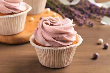 Tasty cupcake with cream on wooden table, closeup