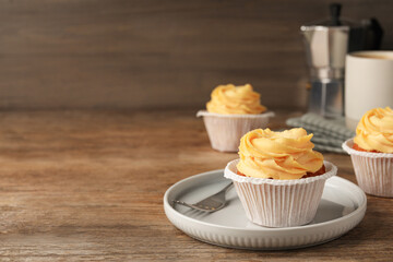 Tasty cupcakes with cream served on wooden table. Space for text