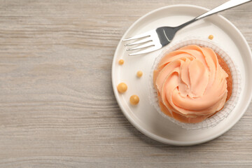 Tasty cupcake served on wooden table, top view. Space for text