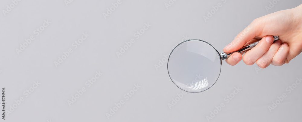 Poster magnifying lens in hand on gray banner with copy space for text.