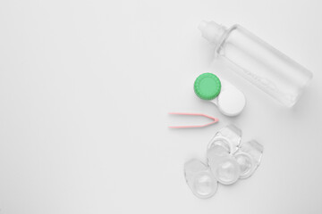 Packages with contact lenses, case, tweezers and drops on white background, flat lay. Space for text