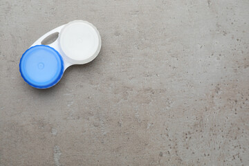 Case with contact lenses on grey table, top view. Space for text