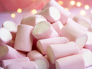 a closeup photo of a tasty pink-white marshmallow with lights on a background