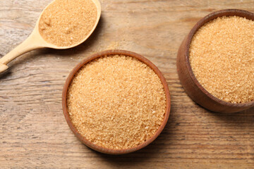 Different dishes with brown sugar on wooden table, flat lay