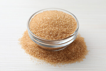 Brown sugar and glass bowl on white wooden table, closeup