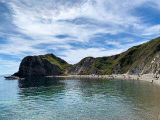 Fototapeta premium Man O'War Beach and Durdle Door on Jurassic Coast, Dorset, England. Scenic bay surrounded by Jurassic Coast rocks. Beach summer holidays. Tourists and locals are enjoying their time at a beautiful la