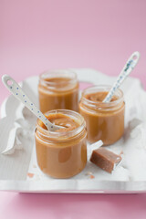 Jars with caramel sauce on tray