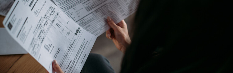 Fototapeta premium Close-up of female hands with pay slips, utility bills, account statements, payment receipts. A woman makes a count of household, family expenses