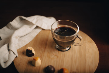 Taza de café, taza de vidrio en mesa de madera, encima de bandeja de madera con bombones de...