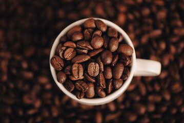 Taza blanca de café, llena de granos de café, cerámica, encima de café, close-up 