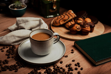 Taza de Café en una mesa de café de madera, con bollos y muffins, granos de café, un libro verde, planta y molino de café, rústico