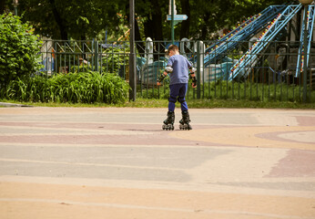 Boy in outfit learns to rollerblade in park