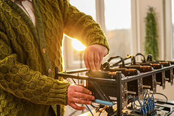 Man adjusting computer graphics in cryptocurrency mining rig