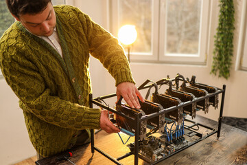 Man adjusting computer graphics in cryptocurrency mining rig
