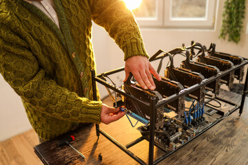 Man adjusting computer graphics in cryptocurrency mining rig