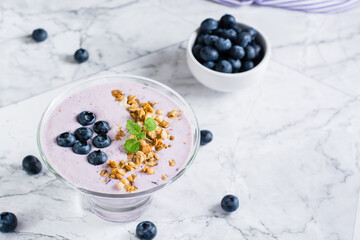 Smoothie bowl with blueberries and granola on the table. Organic antioxidant diet food.