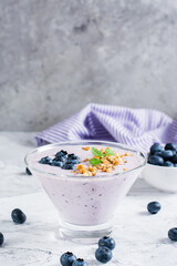Smoothies with blueberries and granola in a bowl. Organic antioxidant healthy food. Vertical view