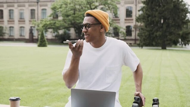 Phone conversation outdoor. Attractive young African American entepreneur is talkingon the phone while sitting in the park.