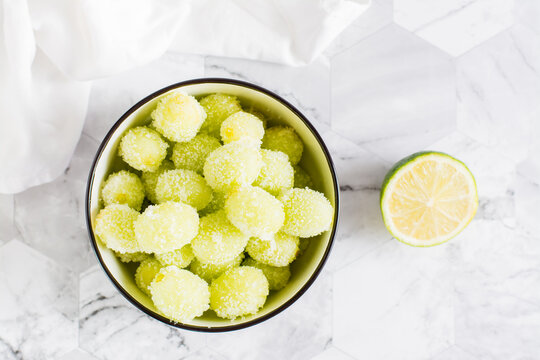 Sour candy grapes in a bowl, lime and sugar for cooking on the table. Social media candy trend. Top and vertical view