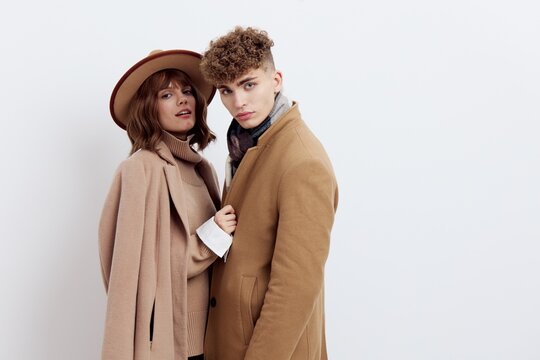 a sweet, beautiful, loving couple stands on a white background in stylish autumn clothes, a woman has a hat on her head, and she gently snuggles up to a man