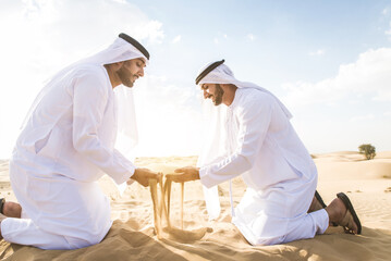 Arabic men in the desert of Dubai wearing traditional emirates clothing