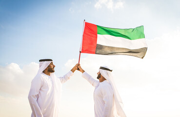 Arabic men in the desert of Dubai wearing traditional emirates clothing
