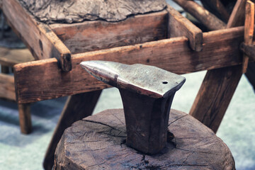 Anvil on a wooden stump in a forge in a rustic old style
