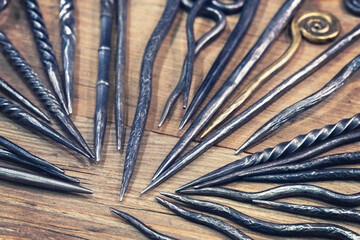 Metal forged products on a wooden background, a pike and an awl are sharp