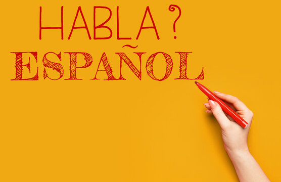 Hand writing text HABLA ESPANOL? (DO YOU SPEAK SPANISH?) on orange background