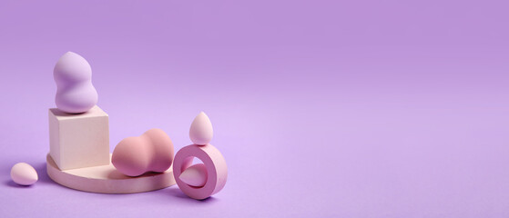 Makeup sponges and decor on lilac background with space for text