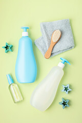 Set of baby toiletries, child organic hygiene and bath accessories, shower gel, shampoo, essential oil, towel on green pastel background. Top view, flatlay