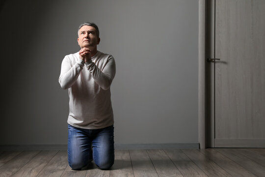 Praying mature man in dark room