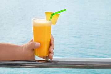 Male hand with glass of fresh tropical cocktail at sea resort