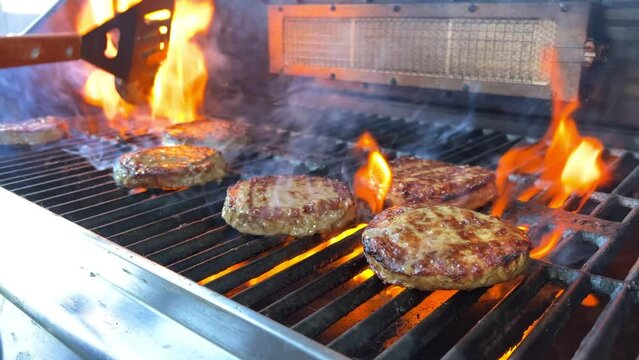 barbecue for a hamburger cooked on an open fire and turned over meat patties ground minced meat ready fried and very tasty turn over with a spatula on fire. the fire just burns and is very tasty.