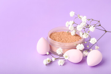 Obraz na płótnie Canvas Jar of makeup powder, sponges and gypsophila flowers on lilac background