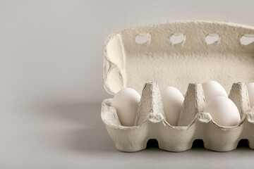 Cardboard holder with chicken eggs on light background, closeup