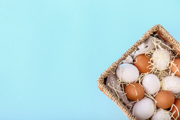 Wicker basket with different chicken eggs on color background