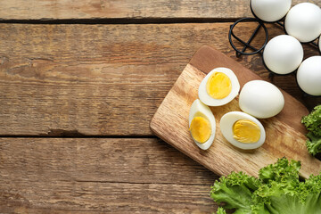 Board with boiled chicken eggs and lettuce on wooden background