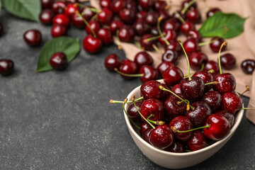 Bowl of ripe cherries with water drops on dark background
