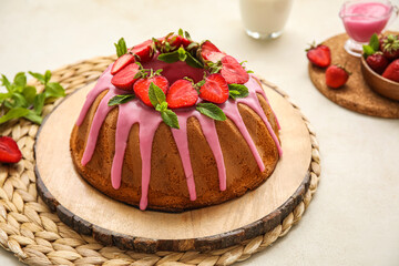 Wooden board with tasty strawberry cake on light background