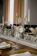 Aesthetic table setting in the restaurant for the holiday with flowers and gold, glasses