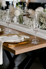 Aesthetic table setting in the restaurant for the holiday with flowers and gold, glasses