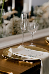 Aesthetic table setting in the restaurant for the holiday with flowers and gold, glasses