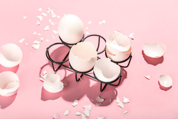 Holder with broken egg shells on color background