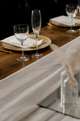 Aesthetic table setting in the restaurant for the holiday with flowers and gold, glasses