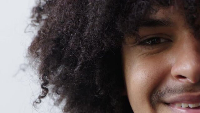Closeup of a black man with curly afro hair smiling and laughing at the camera. Portrait of a cool and young african man with a positive attitude. Face of a confident, charming and cheerful male