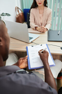Applicant filling cv form during interview with human resources manager