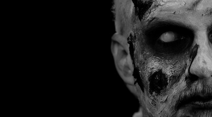 Close-up face of sinister man with horrible scary Halloween zombie makeup making faces, looking...