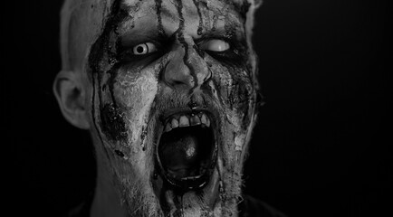 Close-up spooky zombie man face makeup with wounds scars, blood flows and drips on face trying to...